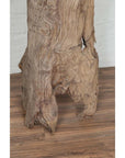 Brown driftwood carving on wood floor against white brick wall, rustic decor indoors, Chiang Mai origin.