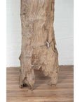 Brown driftwood carving on wooden floor, white brick wall background, Chiang Mai Thailand, indoor setting.