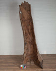 Brown driftwood carving, ancient style, on wood floor with color chart in front, Northern Thailand style.