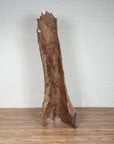 Brown driftwood carving, wood material, placed on a wooden floor indoors against a white brick wall.
