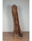 Brown driftwood carving, wood material, on wooden floor with white brick wall background, indoor setting.