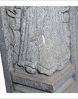 Close-up of gray stone Chinese guardian sculpture, hand-carved, showing robed legs and base.