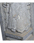 Close-up of gray stone Chinese guardian sculpture, hand-carved, showing robed legs and base.