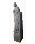 Grey stone hand-carved guardian sculpture of a woman in traditional dress, antique 19th century, indoors.