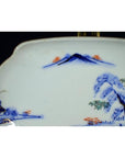 Close-up of blue and white porcelain bowl with hand-painted mountain landscape, trees, and house.
