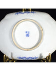 Close-up of the white porcelain underside of an antique Asian hand-painted bowl on a brass stand.