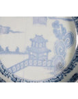 Blue and white porcelain bowl with hand painted pagoda, trees, and figures in traditional Asian landscape style.