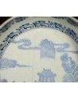 White porcelain bowl with intricate hand painted Asian landscape and architectural designs near the rim, close-up.