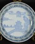 White porcelain bowl with antique Asian hand painted design on ornate gold stand, close-up view.