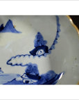 Close-up of blue and white hand painted porcelain bowl with gold scalloped edge, antique Asian design.