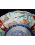Close-up of an antique Asian porcelain bowl with hand painted red, green, blue, and gold designs.