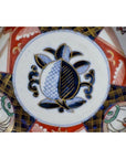 Close-up of antique Asian porcelain bowl with blue and black pomegranate and vibrant floral patterns.