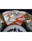 Close-up of red, gold, green, and white porcelain bowl with hand-painted floral and geometric designs.
