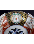 Close-up of antique Asian porcelain bowl with red, gold, green, and blue hand-painted floral patterns.