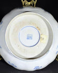 Close-up of the bottom of an antique blue and white porcelain bowl with hand-painted designs and a square maker's mark.