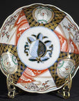 Close-up of red, blue, gold, and black hand-painted porcelain bowl on a gold stand.