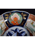 Close-up of antique Asian porcelain bowl with intricate blue, gold, red, and green patterns on the rim.