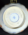 Close-up of the underside of a blue and gold antique Asian hand painted porcelain bowl with maker's mark and metal handles.