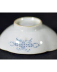 Close-up of blue and white hand painted porcelain dish, upside down, with intricate side pattern on dark background.