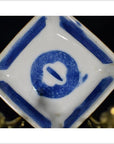 White porcelain dish with hand painted circular symbol and geometric border, antique Asian style, angled view.