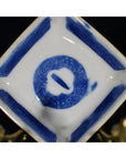 White porcelain dish with hand painted circular symbol and geometric border, antique Asian style, angled view.