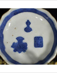 Close-up of blue and white porcelain dish with hand painted Chinese symbols, floral designs, and bold blue rim.