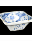 Close-up of antique blue and white hand painted porcelain dish with designs inside and out, on black background.