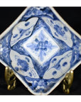 Blue and white hand-painted porcelain dish with floral patterns on a metal display stand.