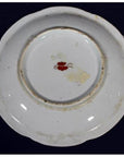 Close-up of the bottom of an antique Asian porcelain plate with a small red mark and light center discoloration.