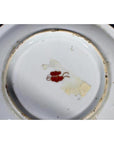 Close-up of base of antique Asian porcelain plate with red floral mark and chipped glaze.