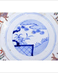 Blue and white hand-painted porcelain plate with central landscape and prancing goats around the border, close-up view.