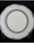 Close-up of the underside of an antique Asian hand-painted porcelain plate with prancing goats on a metal stand.