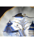 Close-up of blue and gold porcelain plate with hand painted Asian landscape and pagoda island motif.
