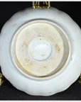 Close-up of the bottom of an antique porcelain plate with Asian hand-painted design, displayed on a metal stand.