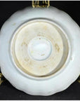Close-up of the bottom of an antique porcelain plate with Asian hand-painted design, displayed on a metal stand.