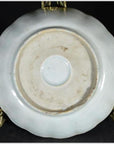 Close-up of the underside of a white porcelain plate with a round foot ring on a gold stand.