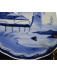 White porcelain plate with hand painted river pavilion and willow grove, close-up of chinoiserie decor pattern.