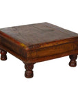 Rustic brown wood Asian prayer or coffee table, square and low with four short rounded legs, close-up view.