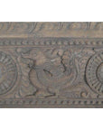 Close-up of antique wooden Indian carving with stylized mythical animal and swirling circular floral patterns.