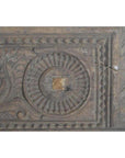Brown carved wood panel with floral, geometric, and circular designs; visible cracks and rich patina, close-up view.