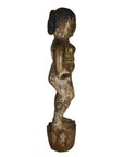 Side view of weathered wooden child statue, Antique Burmese temple carving on round base, white background.