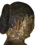 Brown aged wooden sculpture of woman with bun, side view, weathered texture, antique Burmese temple carving.
