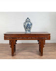 Antique dark wood Chinese altar console table with overhang top, set against a white brick wall and wooden floor.