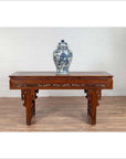 Antique dark wood Chinese altar console table with overhang top, set against a white brick wall and wooden floor.
