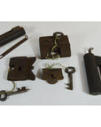 Close-up of five antique metal Chinese and Indian locks with original keys on a white surface.