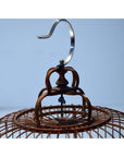 Close-up of brown antique Chinese bird cage top with silver hook on light blue background.