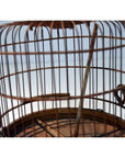 Close-up of antique Chinese bird cage with thin metal bars and wooden perch, highlighting aged metal details.