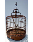 Antique metal Chinese bird cage with hook, empty, against a plain light background.