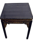 Black lacquer wood altar table with hand-carved sides, showing edge and surface wear.