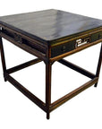 Black lacquered antique Chinese table with decorative side panels and two small drawers, front view.